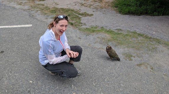 Mika Ritter crouching next to a wild Kea parrot in New Zealand